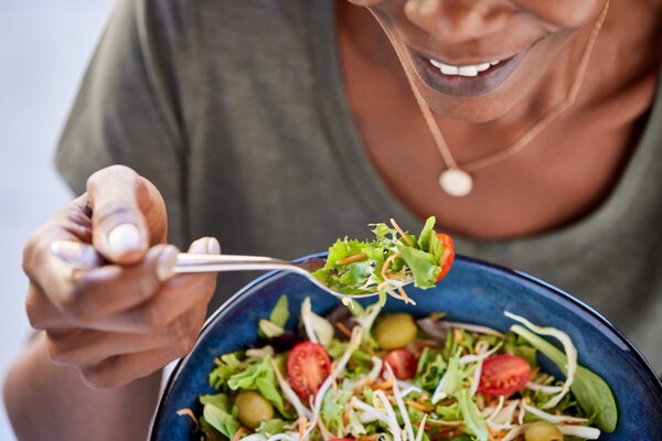 Person holding a bowl of balanced food while sitting at a table